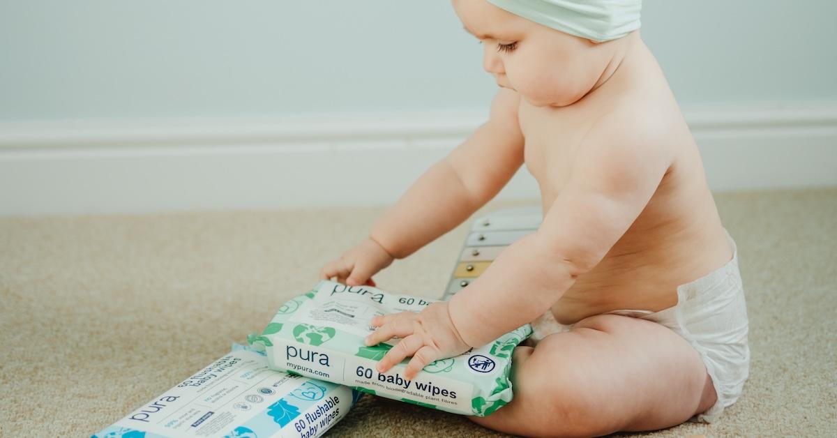 Baby with two packages of baby wipes on carpet